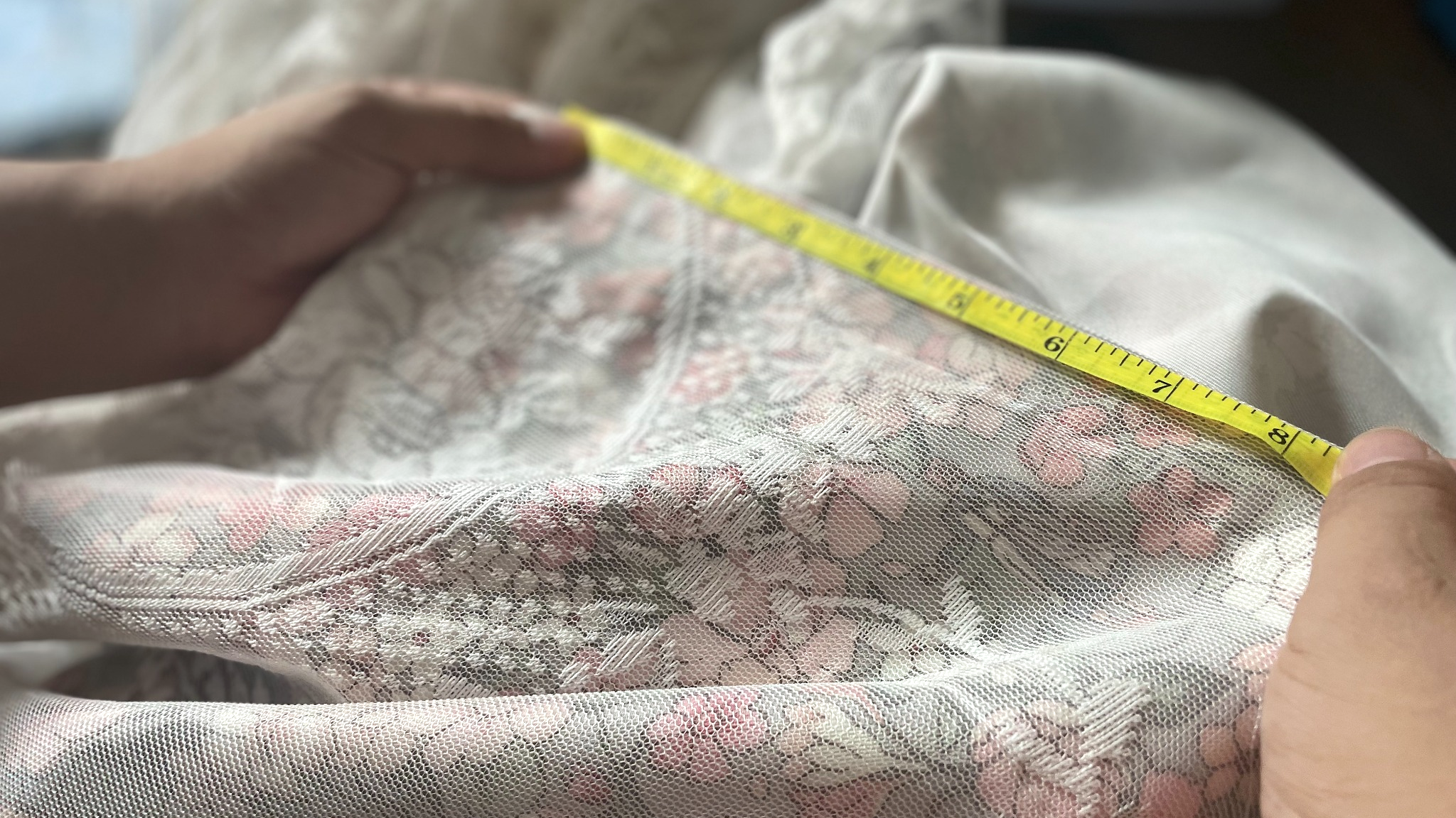 Manual measurement check on a floral lace textile