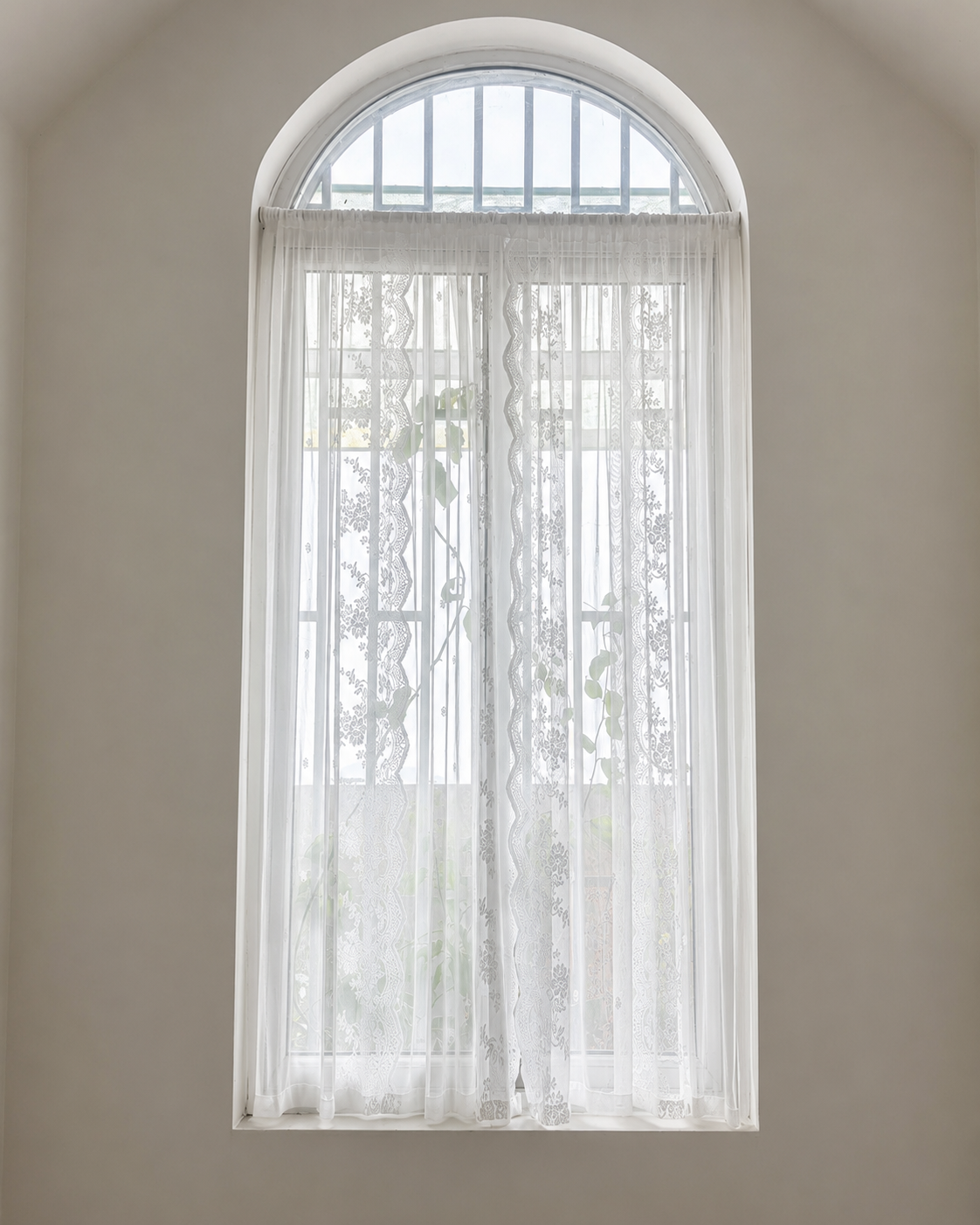 Custom white lace curtain fitted to a tall arched window